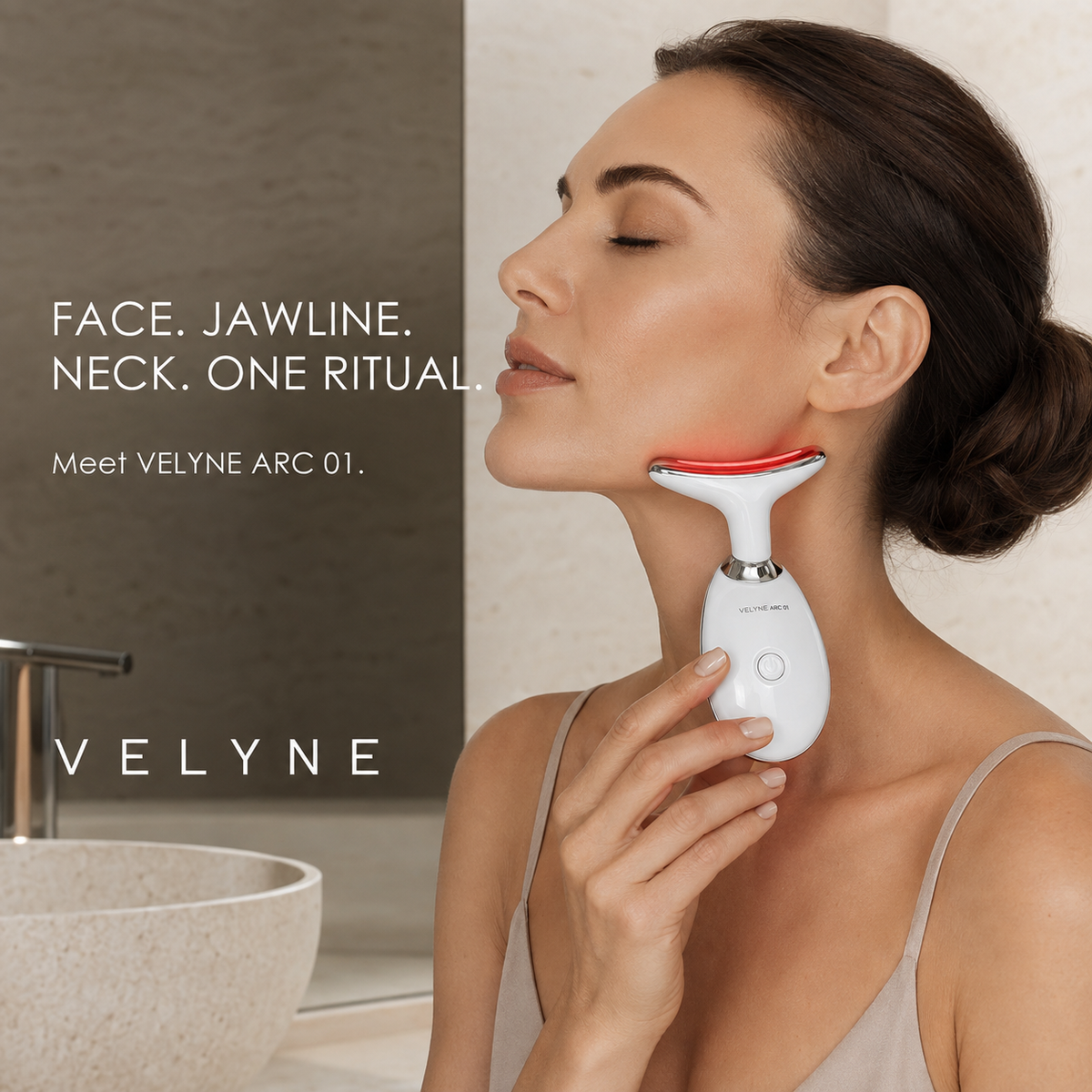 A woman holding VELYNE ARC 01 beneath her jawline, showing the curved contact surface against her contours.